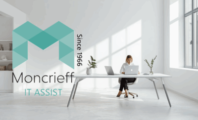 Moncrieff IT Assist branding displayed over a modern office workspace with a person using a laptop at a large desk in a bright, minimalist office environment. Moncrieff IT Assist branding displayed over a modern office workspace with a person using a laptop at a large desk in a bright, minimalist office environment.