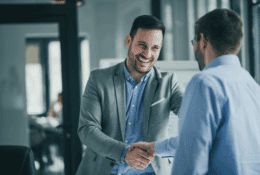 Two business professionals shaking hands in an office, representing trust, collaboration and confidence in business information