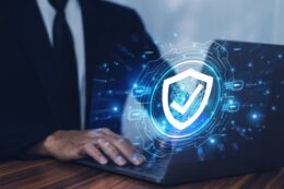 Managed IT service professional working on a laptop with a digital security shield interface, illustrating cyber security, data protection, threat prevention, and secure IT infrastructure.